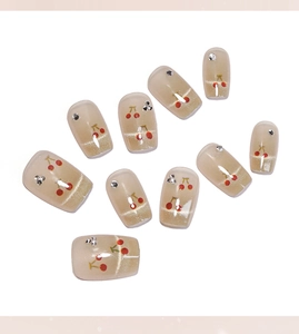 Détail d'ongles French œil-de-chat avec motifs cerises rouges et strass argentés
