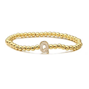 Close-up of golden beaded stretch bracelet with micro-paved cubic zirconia letter Q charm