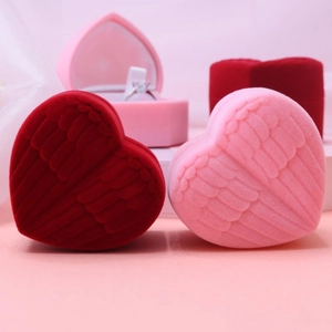 Macro shot of red and pink heart-shaped velvet ring boxes with embossed wing details