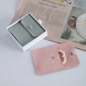 Close-up of microfiber jewelry pouches in pink and grey-green with pearl bracelet