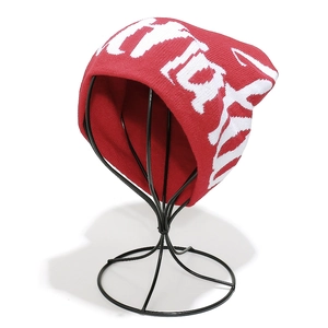 Detailed texture of thick red knit beanie featuring white graffiti-style graphic patterns