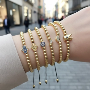 Detail of six-piece gold beaded bracelet set with Hamsa hand and Evil Eye charms