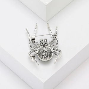 Detailed close-up of a silver spider brooch with textured dotted metal patterns and pin back