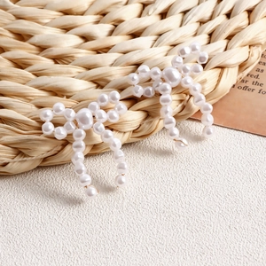 Close-up of handmade faux pearl bow earrings featuring gold wire woven floral design