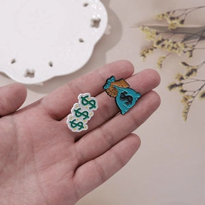 Close-up of dollar sign and money bag pins held in hand with minimalist aesthetic