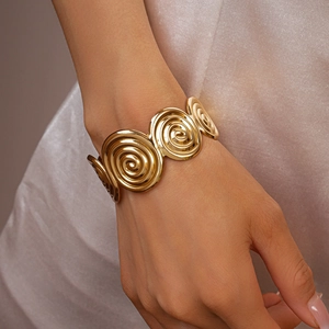 Detailed view of a wide gold spiral textured cuff bracelet on a model's wrist