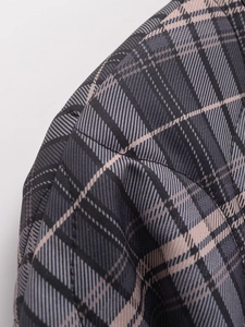 Gros plan sur les coutures et le tissage à carreaux gris de cette veste tendance