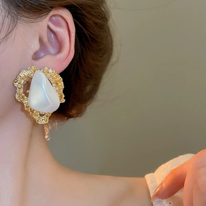 Détail de la boucle d'oreille vintage dorée avec perle blanche portée par un mannequin