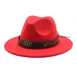 Detail of red fedora hat with brown leather band, bronze floral buckle and metal rivets