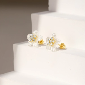 Macro detail of S925 silver flower stud earrings with white petals and gold centers