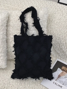 Minimalist black quilted canvas tote bag with fringe details and large capacity for women