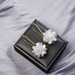Detail of white shell flower earrings with long tassels and sparkling zircon accents