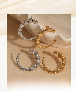 Detailed view of polished gold and silver heart-shaped link C-style hoop earrings