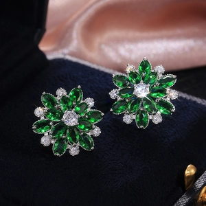 Macro shot of luxury emerald green sunflower earrings with white cubic zirconia accents