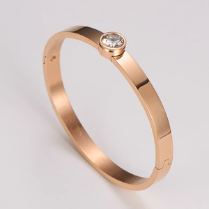 Macro detail of rose gold stainless steel bangle with single inlaid zircon crystal