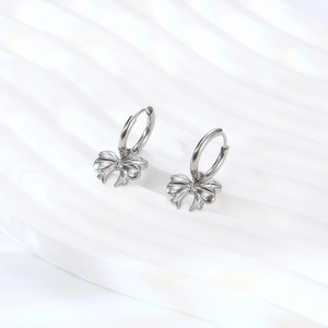 Polished silver titanium steel bow hoop earrings for women on a white textured background