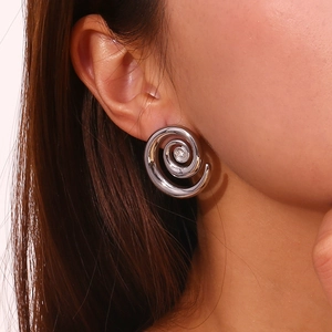 Close-up of minimalist silver swirl earring worn by a model showing modern design