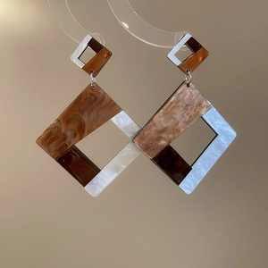 Detail of geometric resin drop earrings featuring brown tortoiseshell and marble patterns