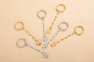 Detail of silver and gold stainless steel heart-shaped keychains with girl pendants