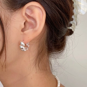 Macro shot of 925 sterling silver twisted rope hoop earring on ear with high polish finish