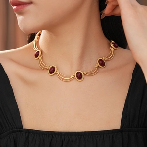 Close-up of vintage gold necklace with five oval red gemstones on a model's neck