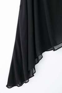 Détail de l'ourlet plissé asymétrique en mousseline noire et du drapé de la robe