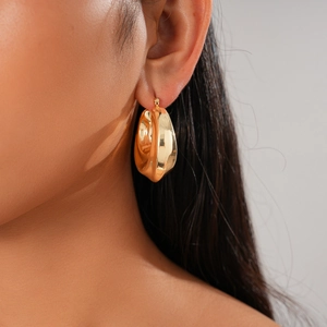 Close-up of gold irregular twisted round earrings worn by model for a stylish look
