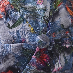 Detail of distressed denim baseball cap with floral print and top button stitching