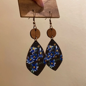 Detail of bohemian teardrop wood earrings with hand-painted blue daisy floral pattern
