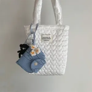 Quilted white heart-pattern tote with daisy charm and crochet bear accessory