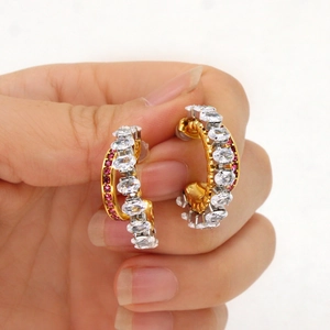 Detail of gold double-layer hoop earrings with white zircon and pink gemstones