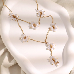 Detail of 18K gold plated necklace featuring woven pearl flowers and elegant Y-shaped drop