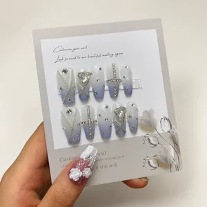 Close-up of blue and white gradient press-on nails with silver chains and rhinestones