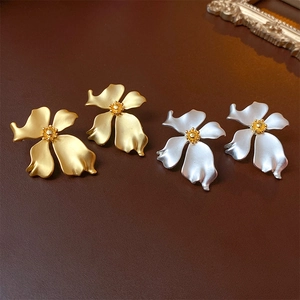 Detailed view of matte flower earrings in gold and silver finish on leather
