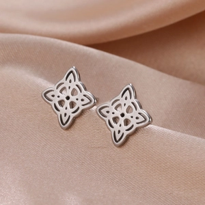 Silver hollow Celtic knot stud earrings in titanium steel on elegant satin fabric