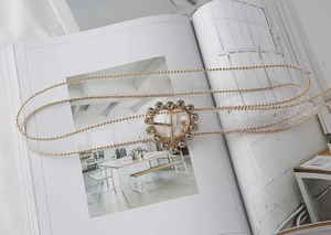 Macro view of gold metal bead belt with rhinestone-encrusted heart buckle on a magazine