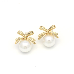 Close-up of elegant gold bow earrings with crystal pavé and hanging round white pearls