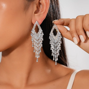 Close-up of cascading silver geometric tassel earrings with zircon crystals on a model