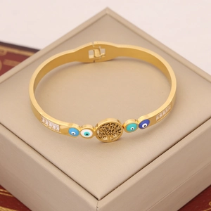 Close-up of golden evil eye bangle with tree of life charm and sparkling crystals