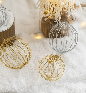 Close-up of glittery gold and silver Christmas ornaments on festive artificial snow scene