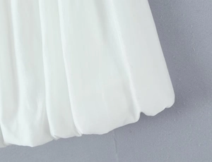 Close-up of white bubble hem top showing pleated texture and lightweight woven fabric