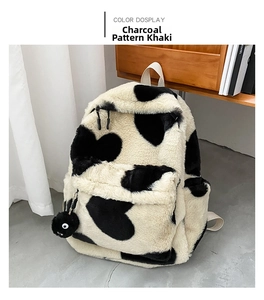 Macro detail of khaki furry backpack with heart patterns and a black pompom charm