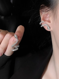 Détail macro de boucles d'oreilles serpent avec zircons et yeux verts sur modèle
