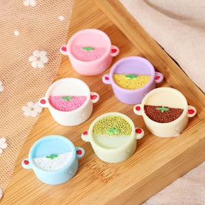 Top view of six miniature resin cooking pots in pastel colors on a rustic wooden tray
