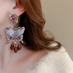Detail of crystal butterfly tassel earring with enamel wings on model side profile