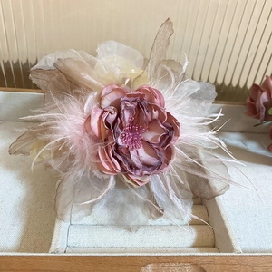 Detail of organza flower hair claw clip with gradient pink petals and feather accents