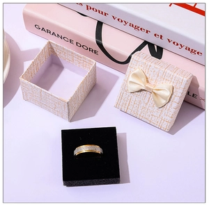 Detail of a matte gold ring with silver glitter next to a textured beige bow gift box