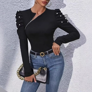 Detail of elegant black long-sleeve top featuring pearl accents and asymmetrical zipper neck