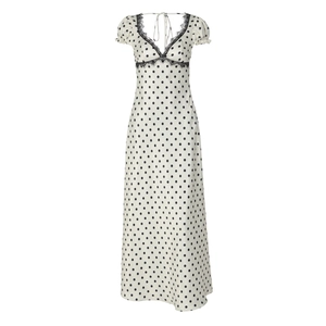 Dettaglio dello scollo a V con pizzo nero su un abito bianco a pois in stile francese