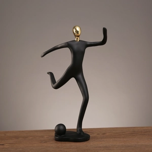 Statue de footballeur en résine noir mat avec tête dorée brillante sur table bois